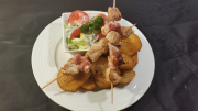 Turkey breast skewer with feta coated with bacon, round potato, tzatziki