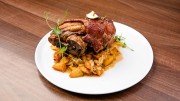 Crispy pork knuckle with fried sauerkraut-potato cubes, and roasted red onion